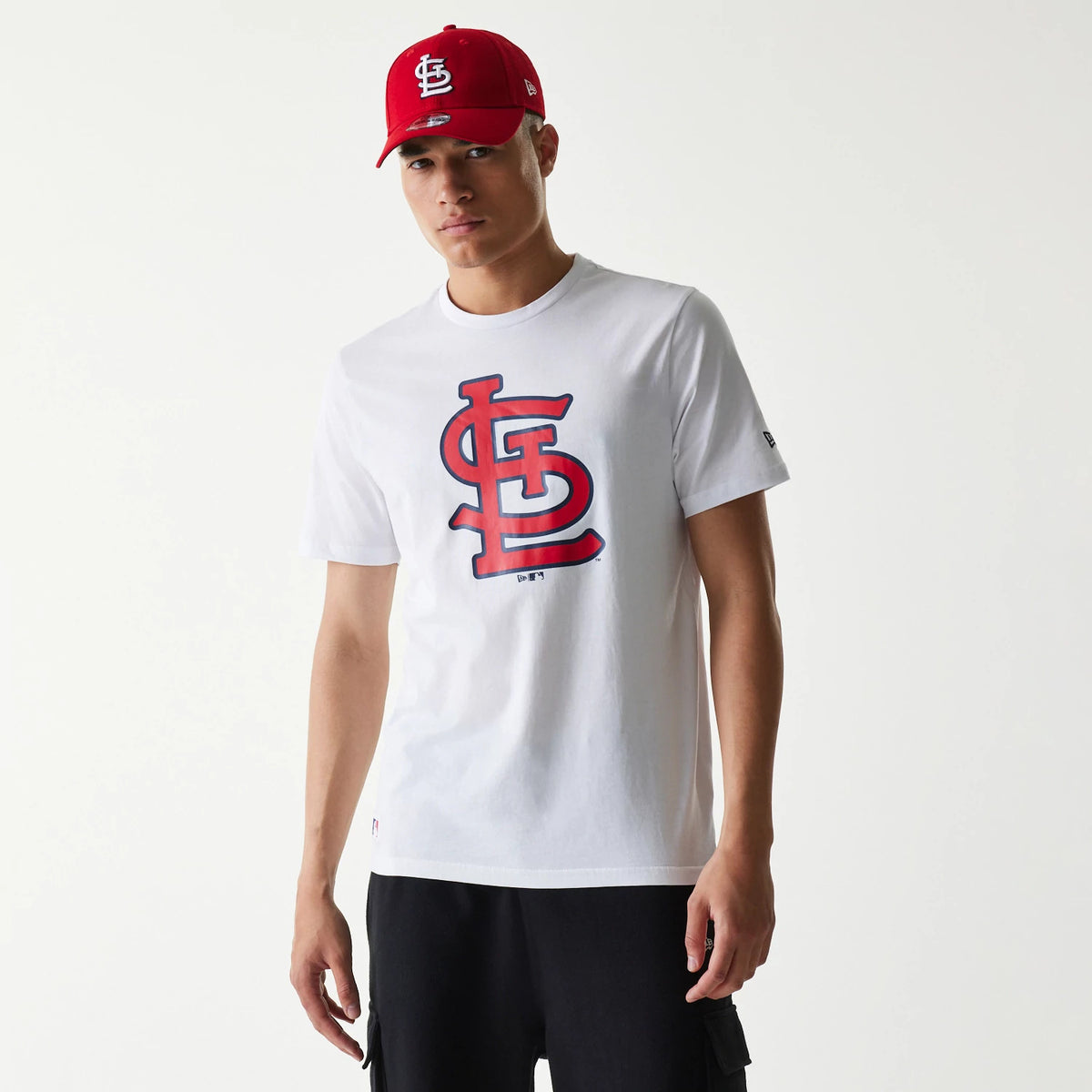 New Era St. Louis Cardinals MLB Regular White T-Shirt, on-model view showing the white shirt with a large red and navy outlined logo on the front, paired with a red cap featuring an embroidered white logo on the front panel.