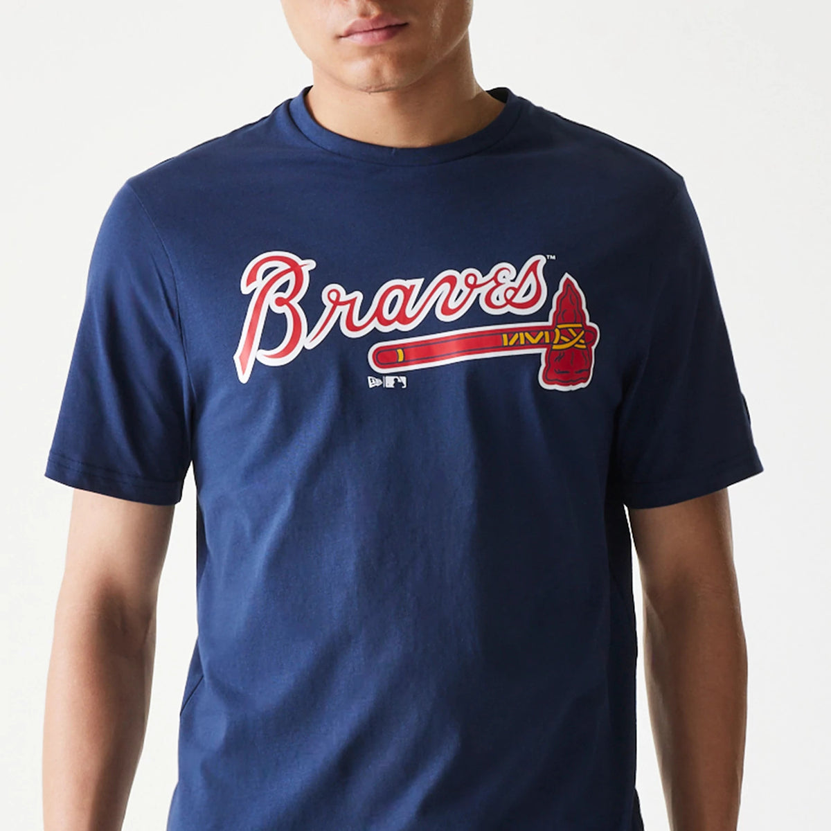 New Era Atlanta Braves MLB Regular Dark Blue T-Shirt, front view showing the Braves script logo across the chest in white and red with an illustrated tomahawk, worn by a person in a dark blue crew neck style.