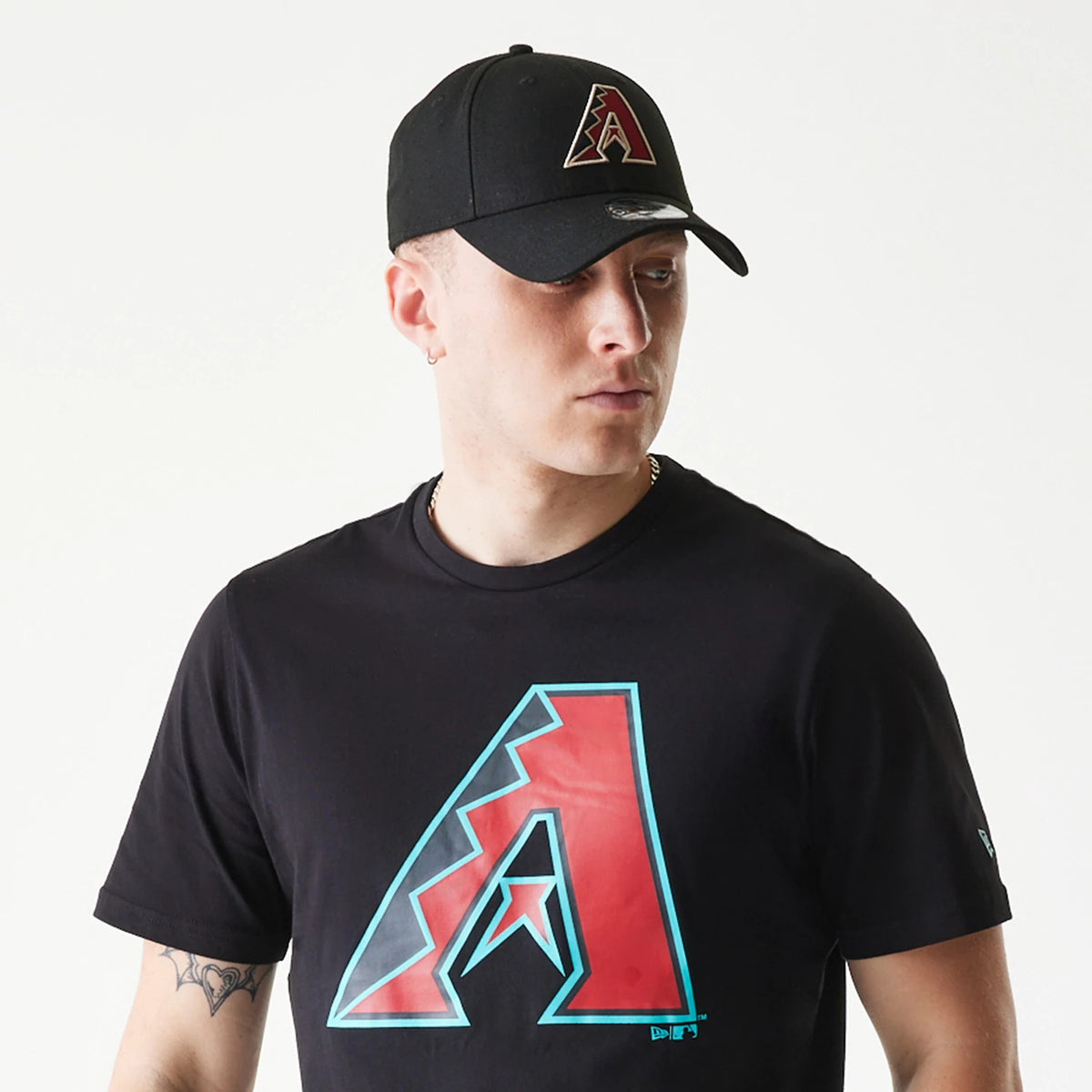 New Era Arizona Diamondbacks MLB Regular Black T-Shirt, on-model view showing a large red and blue Arizona Diamondbacks logo on the chest, paired with a black cap featuring a raised team logo on the front above the peak.