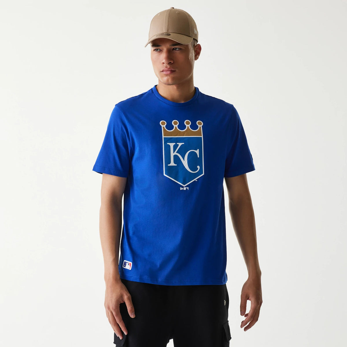 New Era Kansas City Royals MLB Regular Blue T-Shirt, on-model view showing a large printed shield logo with a crown on the chest, a New Era tag on the side and a small MLB logo near the hem in the corner.