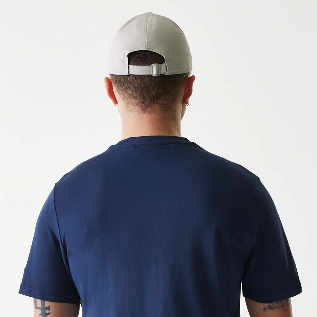 New Era Houston Astros MLB Regular Dark Blue T-Shirt, rear view showing the dark blue fabric worn by a person with a light grey cap adjusted by a strap at the back and an embroidered eyelet on each panel.