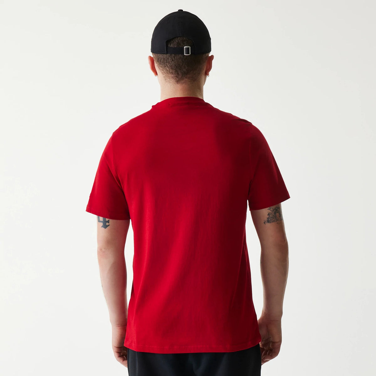 New Era Cincinnati Reds MLB Regular Red T-Shirt, rear view showing the solid red fabric with short sleeves and a man wearing the T-shirt paired with a black cap featuring a debossed logo on the back.