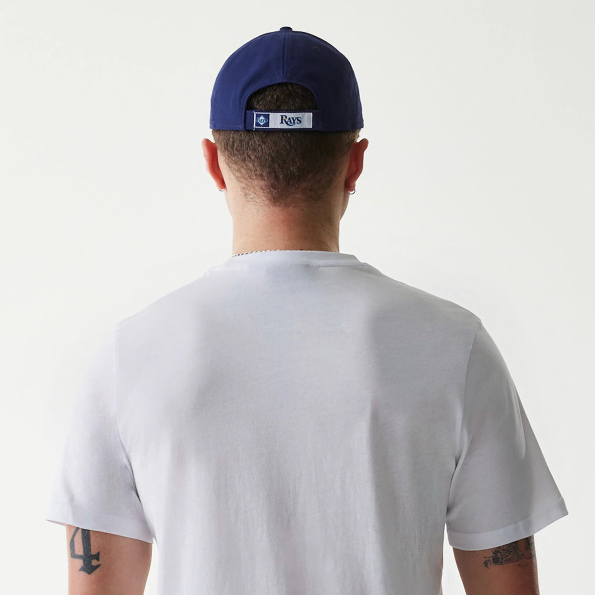 New Era Tampa Bay Rays MLB Regular White T-Shirt, on-model rear view showing the plain white back of the t-shirt, a blue cap worn with an embroidered Rays logo patch centred above the opening on the cap.