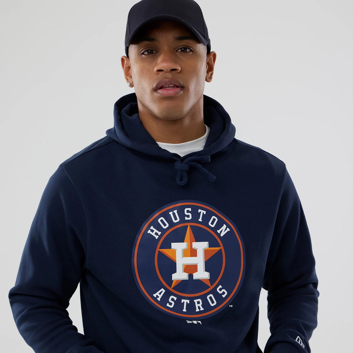 New Era Houston Astros MLB Dark Blue Pullover Hoodie, on-model view showing the dark blue hoodie with a prominent Houston Astros logo on the chest, drawstrings at the hood and a small embroidered New Era logo on the sleeve.