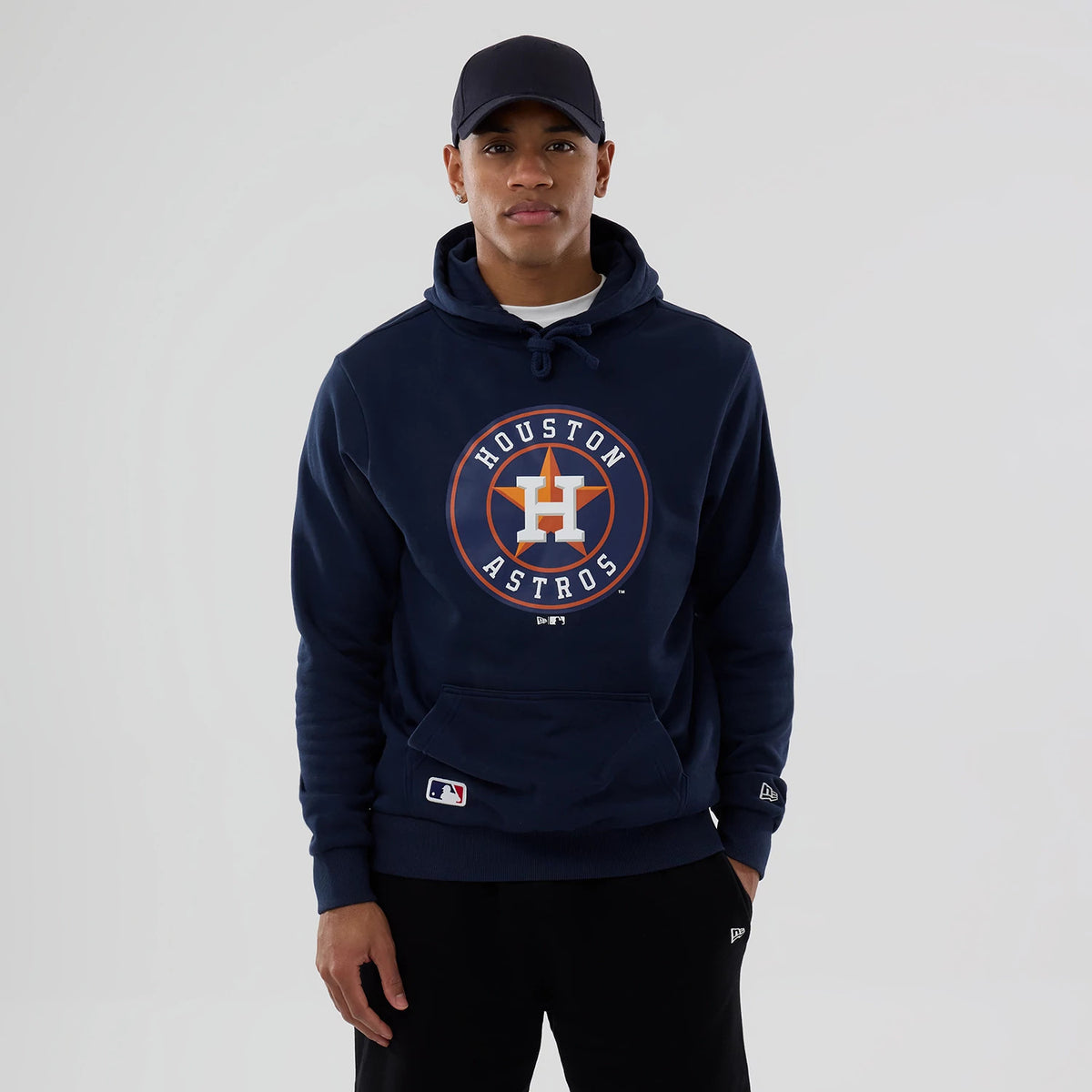 New Era Houston Astros MLB Dark Blue Pullover Hoodie, on-model view showing a large Houston Astros logo centred on the chest, a debossed New Era logo on the left sleeve cuff, and an embroidered MLB logo on the pocket.