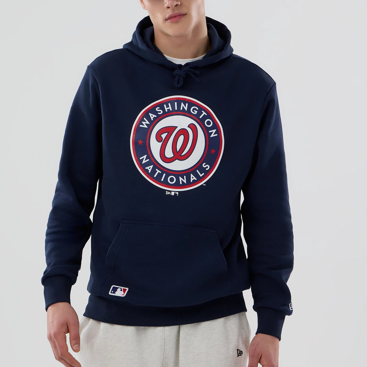 New Era Washington Nationals MLB Dark Blue Pullover Hoodie, front view showing a large circular logo with the team name and emblem in red and white centred on the chest, with a small New Era logo tag on the lower left pocket.