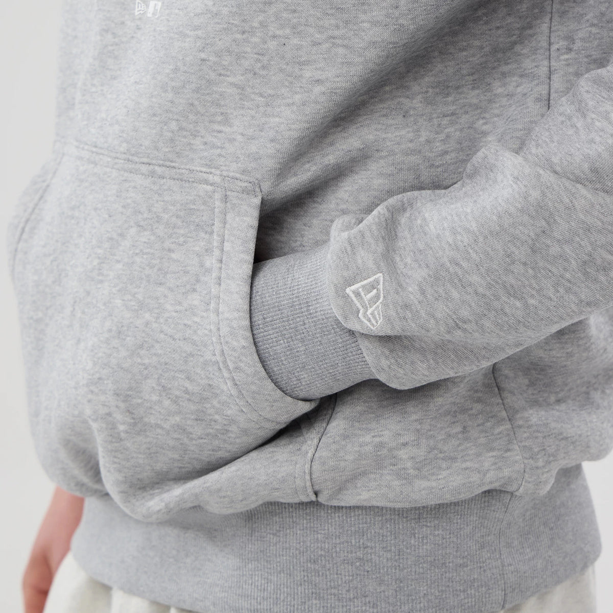 New Era Philadelphia Phillies MLB Grey Pullover Hoodie, side view showing the light grey fabric with a front pocket, ribbed cuff featuring a raised New Era logo on the sleeve close-up.
