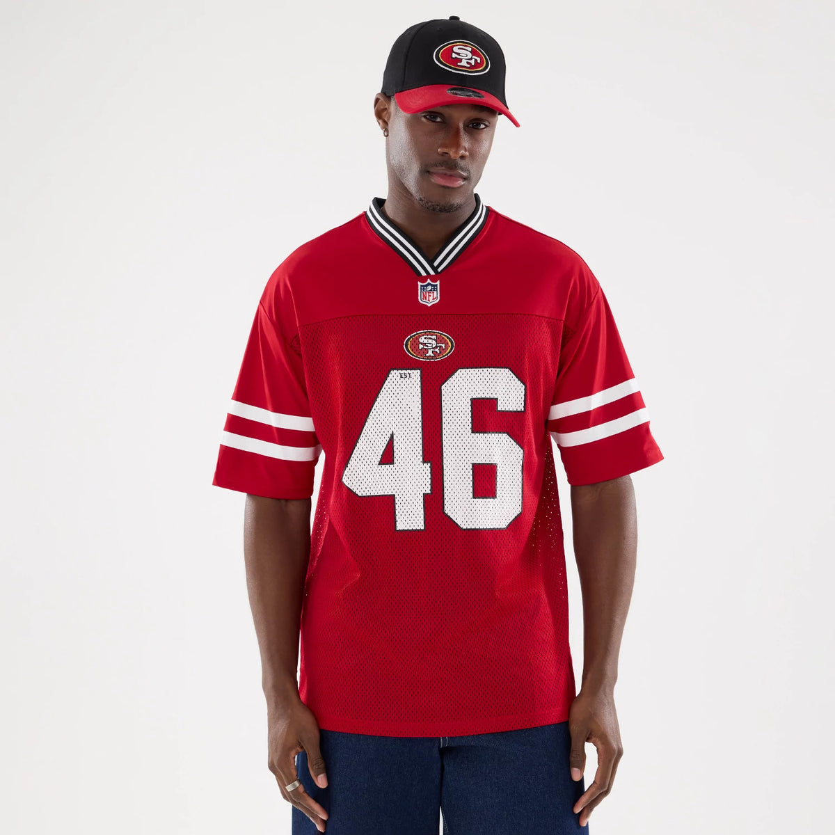 New Era San Francisco 49ers NFL Mesh Red Mesh Jersey, front view on a model wearing a matching red and black cap, showing the embroidered 49ers logo centred on the chest above large white number 46 with striped sleeves.