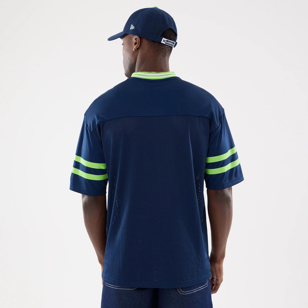 New Era Seattle Seahawks NFL Mesh Dark Blue Mesh Jersey, back view on a model with a matching cap, showing lime green stripe accents on the sleeves and a contrasting green collar, enhancing the sporty mesh design.