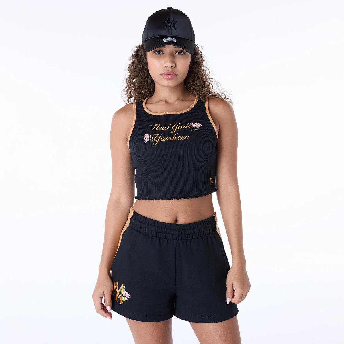 New Era New York Yankees Womens MLB Floral Black Vest, front view on a model wearing a black Yankees cap, showing the floral motif and New York Yankees script embroidery across the chest, with orange trim details.