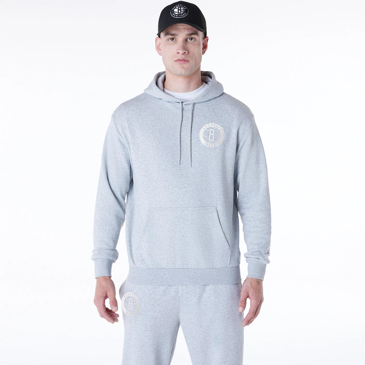 New Era Brooklyn Nets NBA League Essential Grey Oversized Pullover Hoodie, front view showing the light grey hoodie with a debossed Brooklyn Nets logo on the left chest, drawstrings hanging from the hood and a kangaroo pocket at the front.