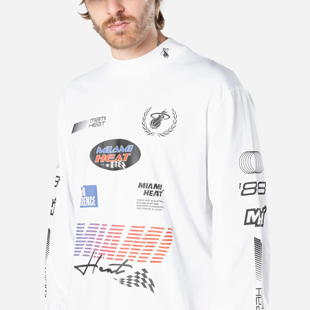 New Era Miami Heat Modern Driver White Long Sleeve T-Shirt, front view showing multiple logos including a Miami Heat logo with laurels, large Miami Heat text in red and blue on the chest, and various black graphics on the long sleeves and collar.