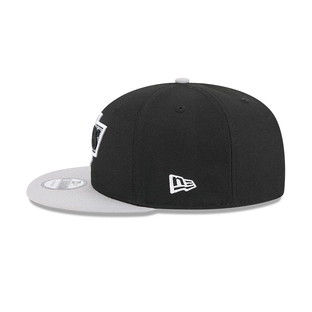 LA Kings NHL Evergreen Black New Era 9FIFTY Snapback Adjustable Cap, side view showing the embroidered New Era flag logo on the left side, a structured black crown, and a grey flat visor with a 9FIFTY size sticker.