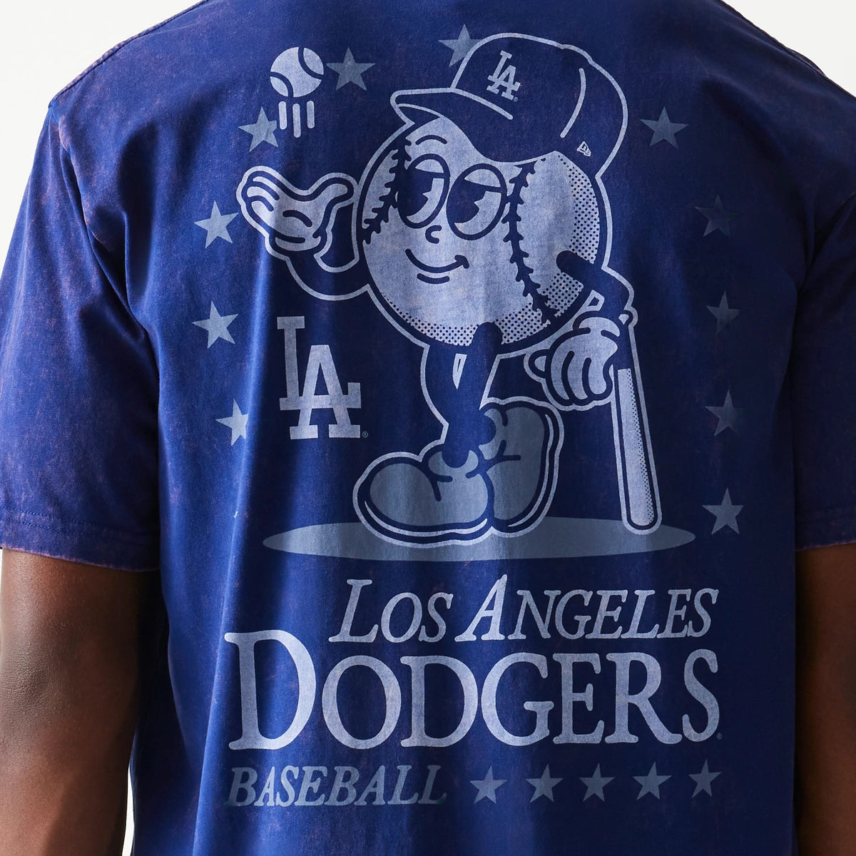 New Era LA Dodgers MLB Character Dark Blue T-Shirt, back view featuring a large graphic of a cartoon baseball character wearing an LA cap, surrounded by stars with the LA logo to the right and Los Angeles Dodgers Baseball text below.