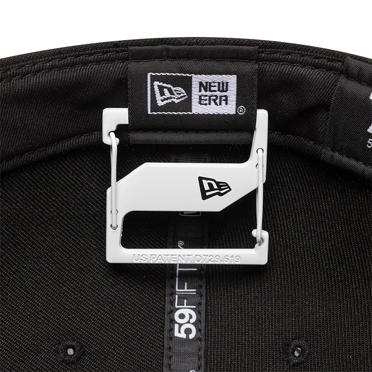 New Era White Cap Clip, inside view with the clip attached to the black taping of a 59FIFTY cap, displaying the New Era flag logo on the white clip and the inner branded taping with black stitching.