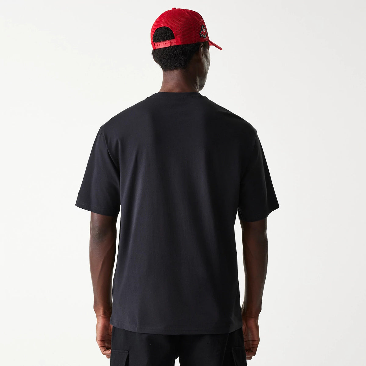 New Era Chicago Bulls NBA Palm Tree Black Oversized T-Shirt, rear view showing a plain black back with short sleeves, on-model with a debossed New Era logo on a red cap worn by the model.