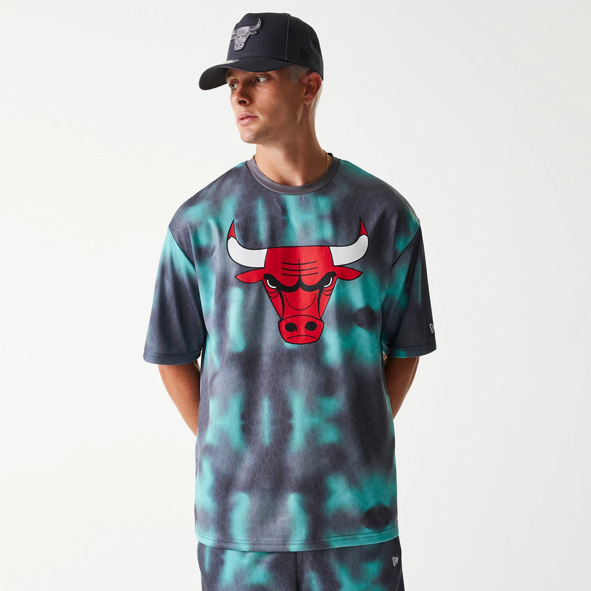 New Era Chicago Bulls NBA All Over Print Green Oversized T-Shirt, on-model view showing a large red and white bull logo centred on the chest with a tie-dye effect in green and dark shades covering the entire fabric.