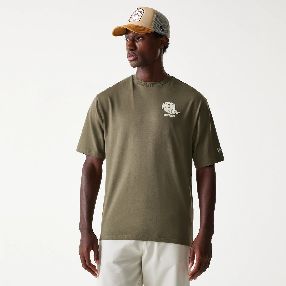 New Era Graphic Green Oversized T-Shirt, front view showing an olive-green colour with a white printed graphic on the left chest and a raised New Era logo on the left sleeve, worn by a person standing.