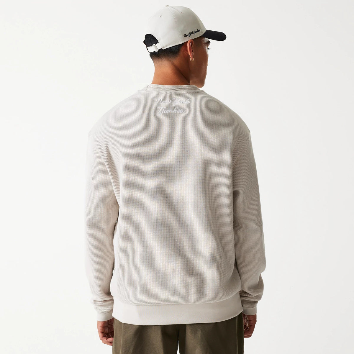 New Era New York Yankees MLB Waffle Cream Oversized Crew Neck Sweater, back view on a model wearing a cream cap, showing the white Yankees embroidery below the neckline and the textured waffle fabric.