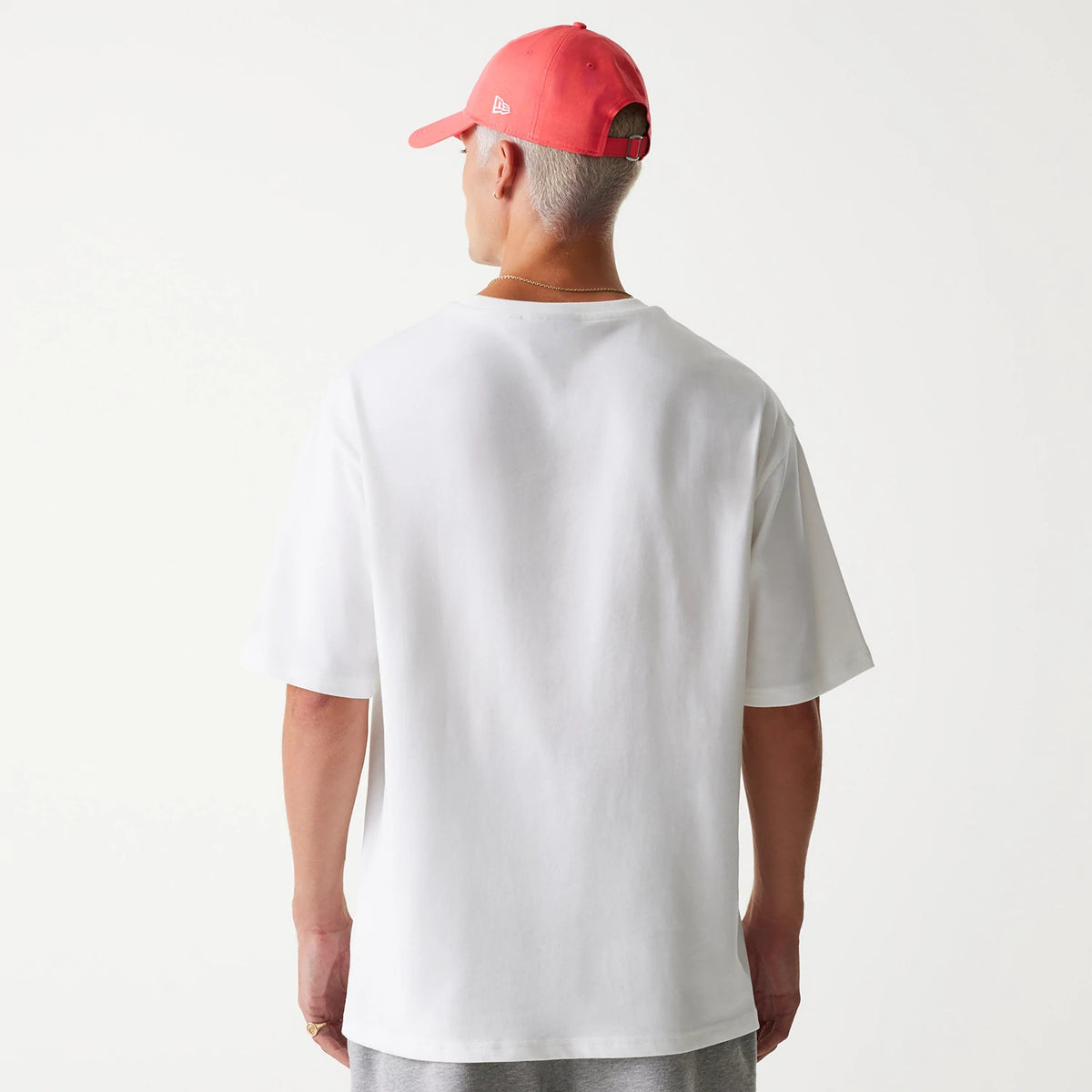 New Era New York Yankees MLB World Series 1999 White Oversized T-Shirt, on-model view from the back showing the plain white fabric and relaxed fit, worn with a red cap featuring a debossed New Era logo on the side.