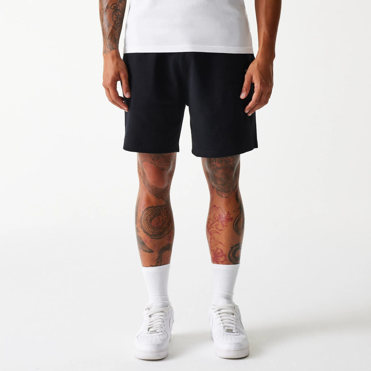 New Era LA Dodgers MLB Pique Black Shorts, front view showing the solid black design worn by a model, reaching above the knees, with no visible logos or detailing on the fabric.