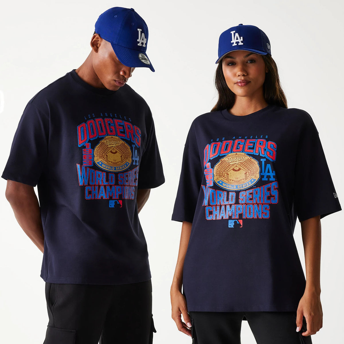 New Era LA Dodgers MLB World Series Navy Oversized T-Shirt, on-model view showing the large blue and red Dodgers World Series graphic printed on the navy fabric, with a raised logo on a blue cap worn by both models.