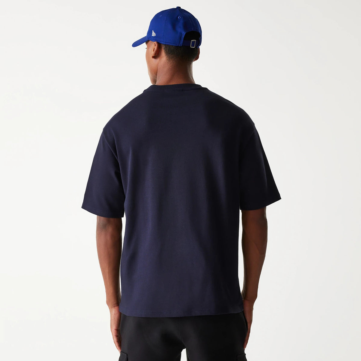 New Era LA Dodgers MLB World Series Navy Oversized T-Shirt, rear view showing the plain navy back with a relaxed fit, short sleeves, and a raised New Era logo on a blue cap worn by the person.