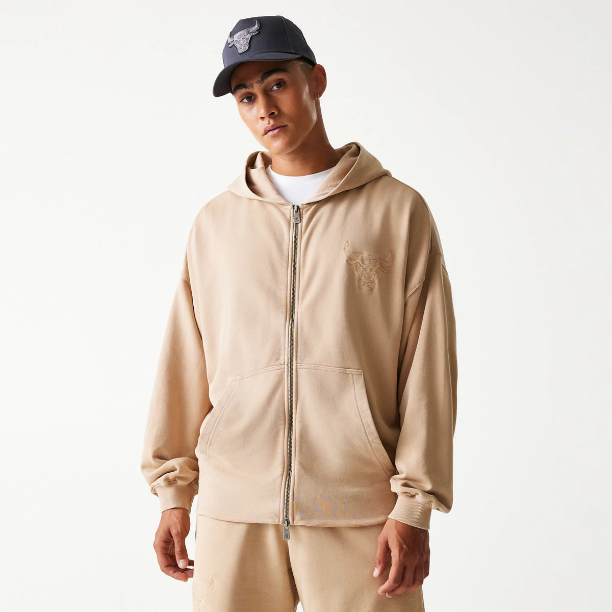 New Era Chicago Bulls NBA Washed Beige Full Zip Hoodie, front view showing a beige hoodie with a full zip closure, an embossed Chicago Bulls logo on the left chest, and a hood resting on the shoulders.