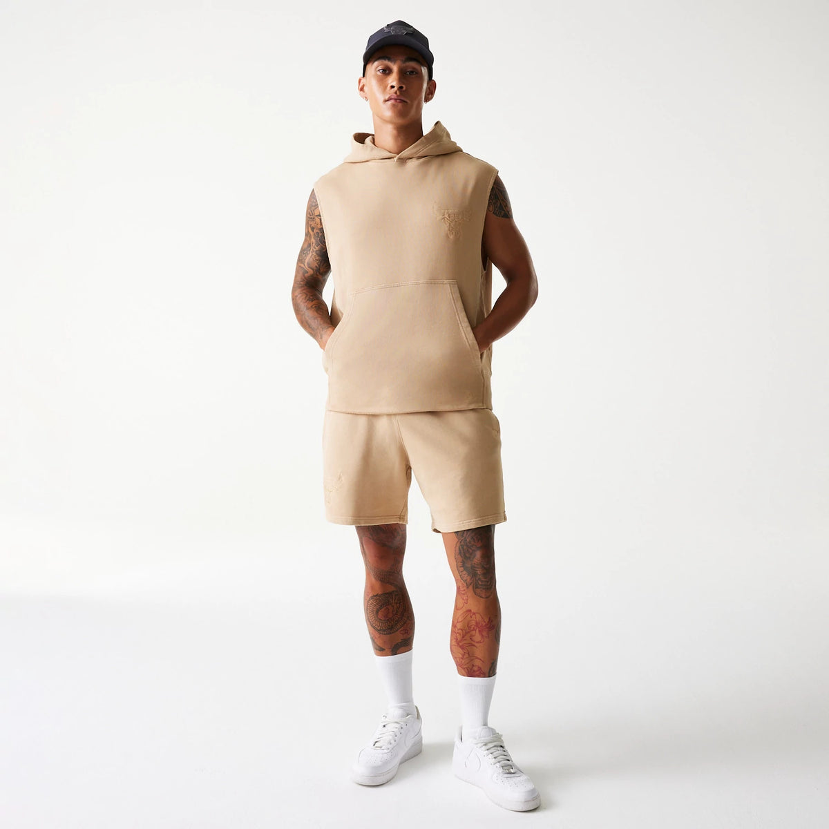 New Era Chicago Bulls NBA Washed Beige Shorts, on-model view showing the beige shorts worn with a matching sleeveless hoodie, a drawstring at the waist, and a small embossed logo on the left thigh.