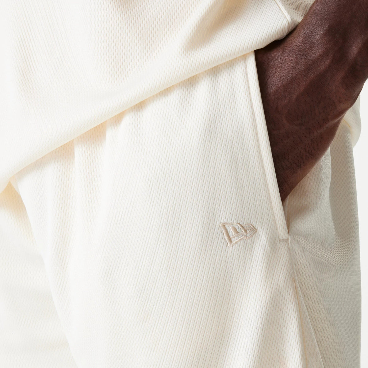 New Era LA Lakers NBA Tonal Open White Mesh Shorts, side view showing a debossed New Era logo near the pocket on the white mesh fabric, with a subtle texture visible on the surface and stitching along the side seam.