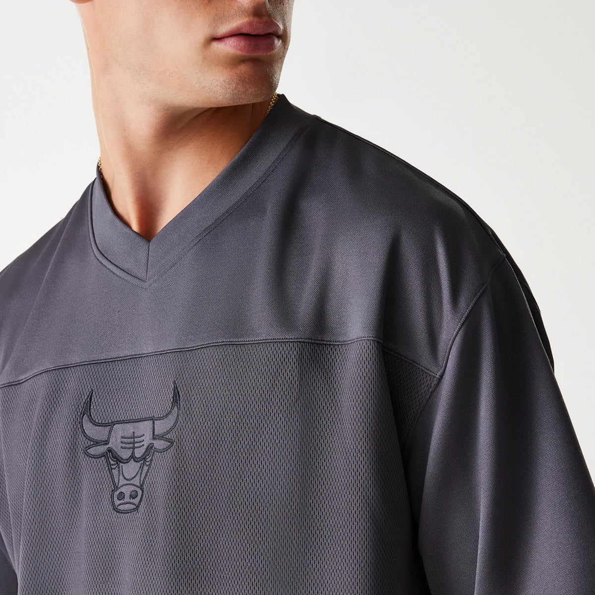 New Era Chicago Bulls NBA Tonal Dark Grey Mesh Jersey, front view on a model showing the v-neck collar and the tonal Chicago Bulls logo centred on the textured mesh fabric across the chest.