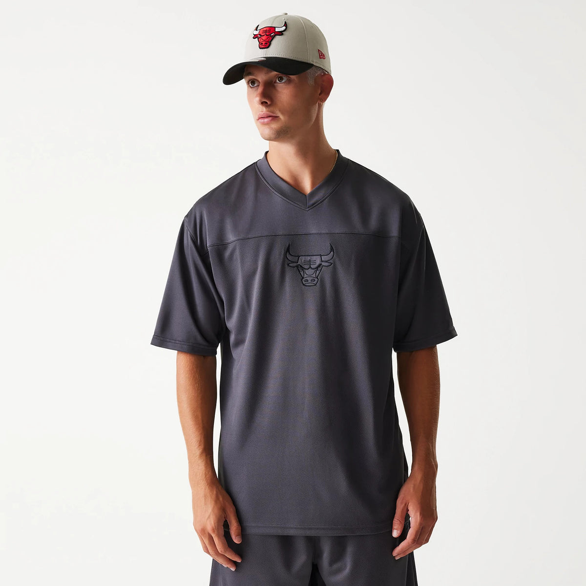 New Era Chicago Bulls NBA Tonal Dark Grey Mesh Jersey, front view on a model wearing a matching cap, featuring the black embroidered Bulls logo on the chest and a V-neckline.