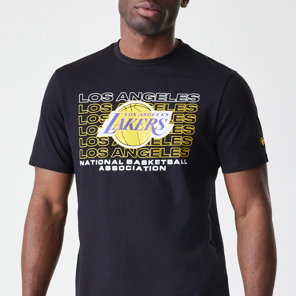 New Era LA Lakers NBA Stack Wordmark Black T-Shirt, front view featuring a graphic with stacked 'Los Angeles Lakers' text and a basketball logo centred on the chest, worn by a model with a small debossed New Era logo on the sleeve.
