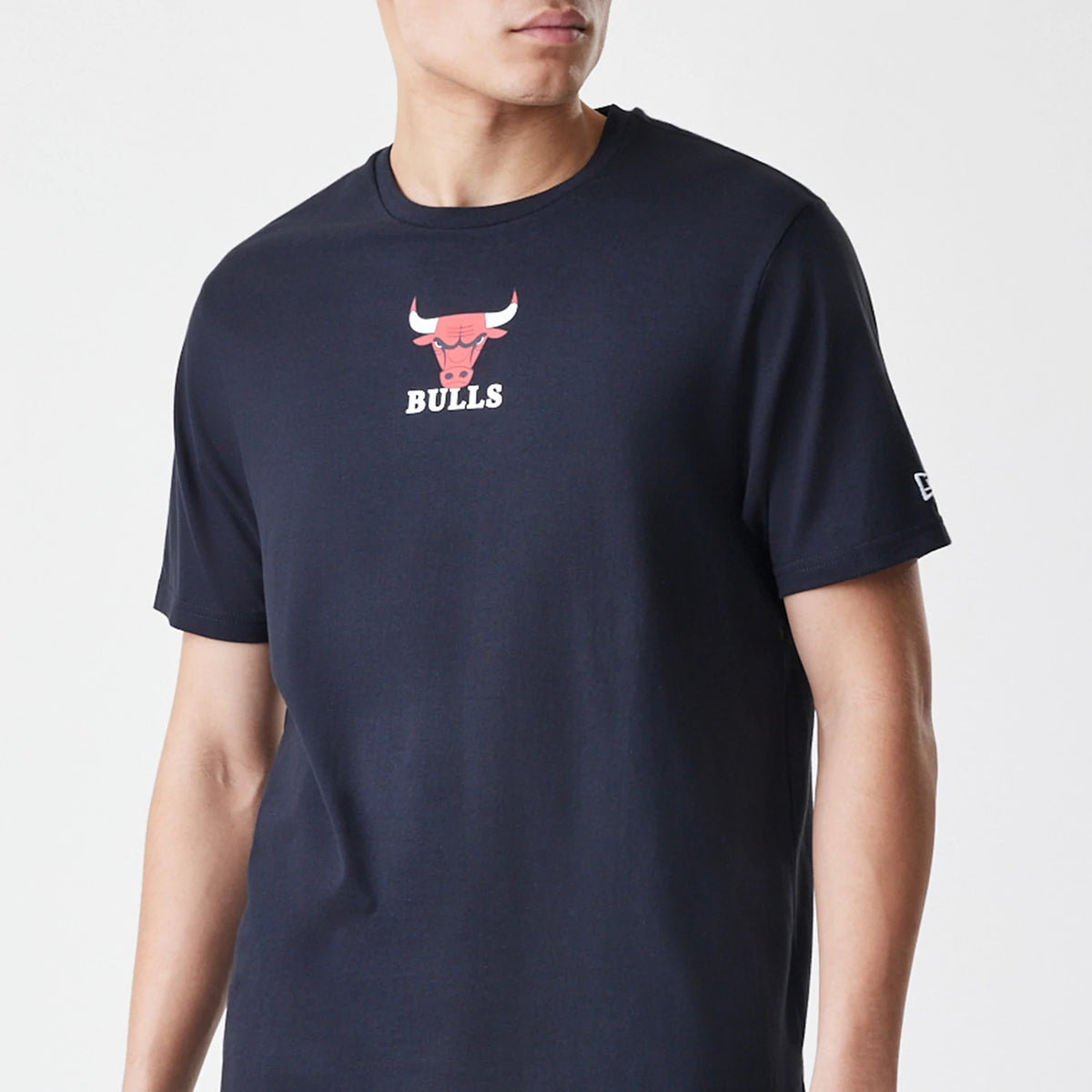New Era Chicago Bulls NBA Logo Black T-Shirt, on-model view showing the red and white bull logo centred on the chest, short sleeves with a white raised New Era logo on the left sleeve against a plain black fabric.
