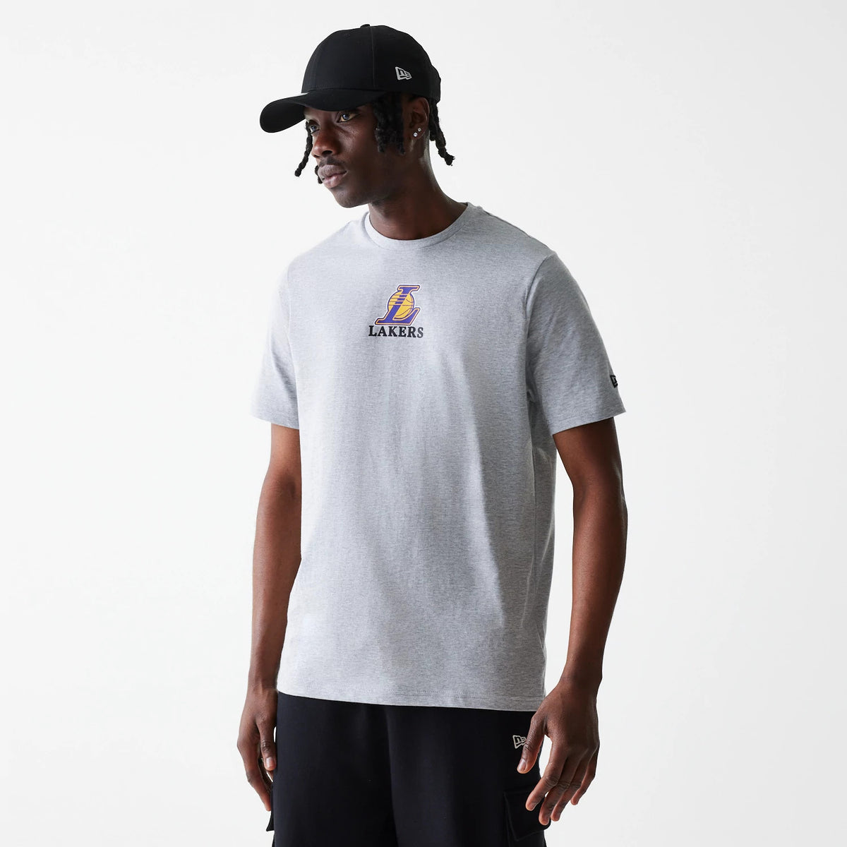 New Era LA Lakers NBA Logo Grey T-Shirt, on-model view showing the grey shirt with a raised LA Lakers logo centred on the chest and a New Era logo on the sleeve, model wearing a black cap with a raised logo on the side.