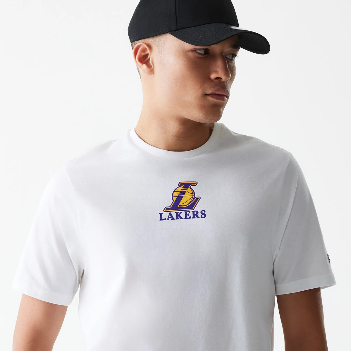 New Era LA Lakers NBA Logo White T-Shirt, on-model view showing the front of the white shirt with a large purple and gold LA Lakers logo centred on the chest and a small debossed logo on the left sleeve.