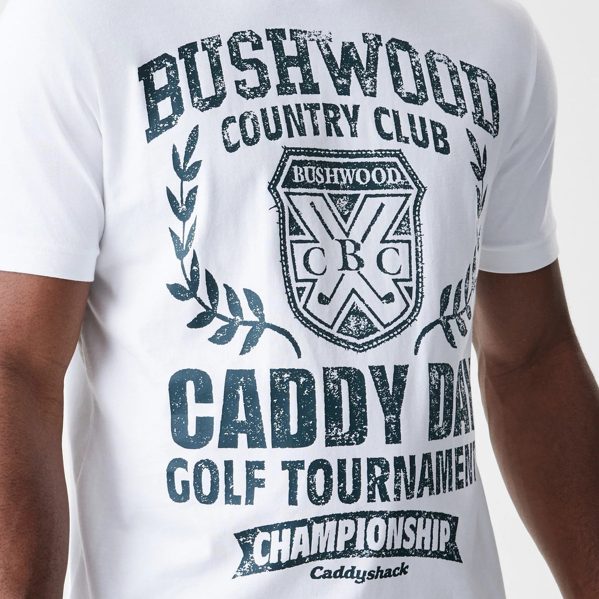 New Era Caddyshack Caddy Day Tournament White T-Shirt, front view showing a large distressed print with the text Bushwood Country Club and a crest logo centred on the chest, surrounded by laurel branches and additional tournament text below.