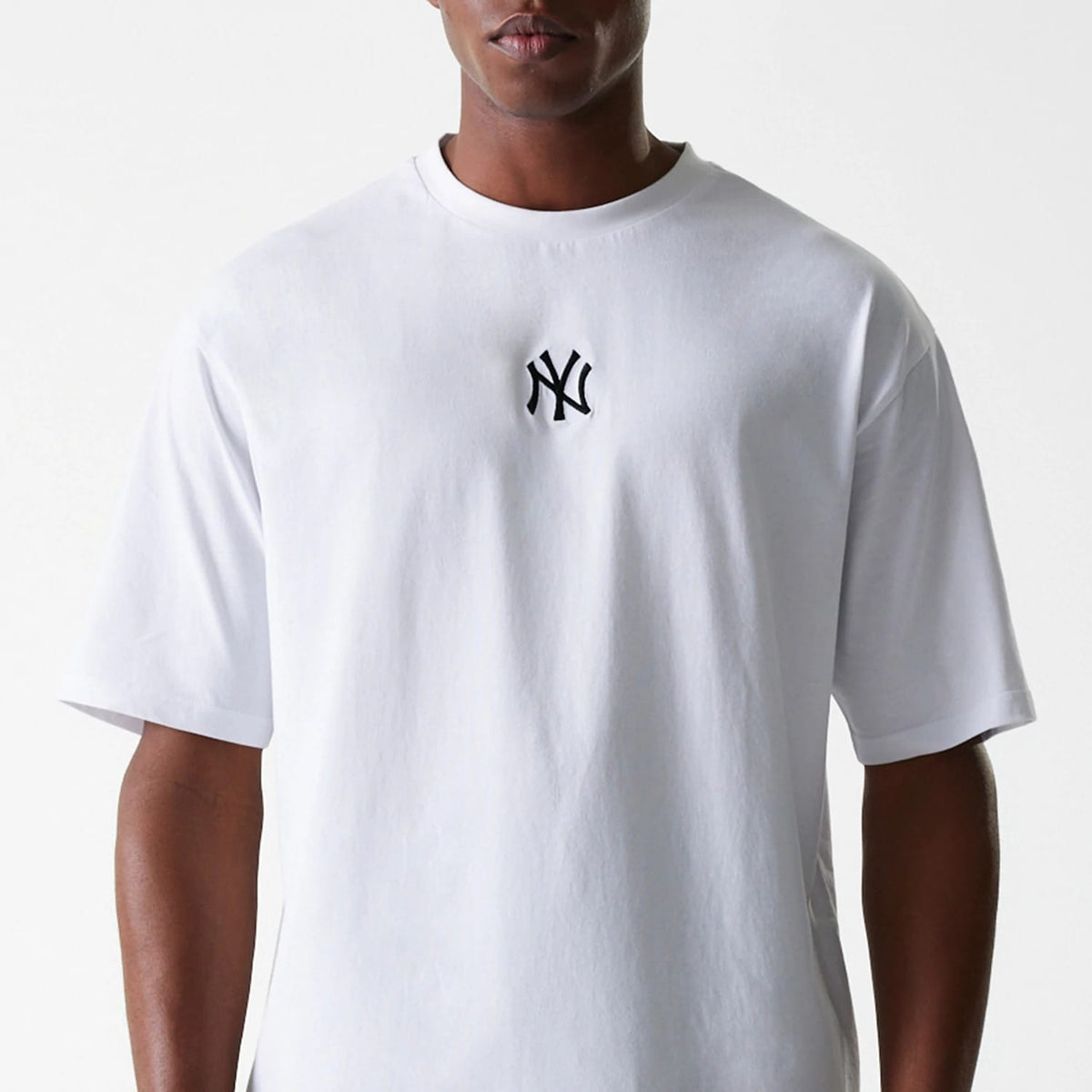 New Era New York Yankees MLB League Essential White Oversized T-Shirt, front view showing a black embroidered New York Yankees logo centred on the chest of the plain white oversized t-shirt, short sleeves and a round neckline.