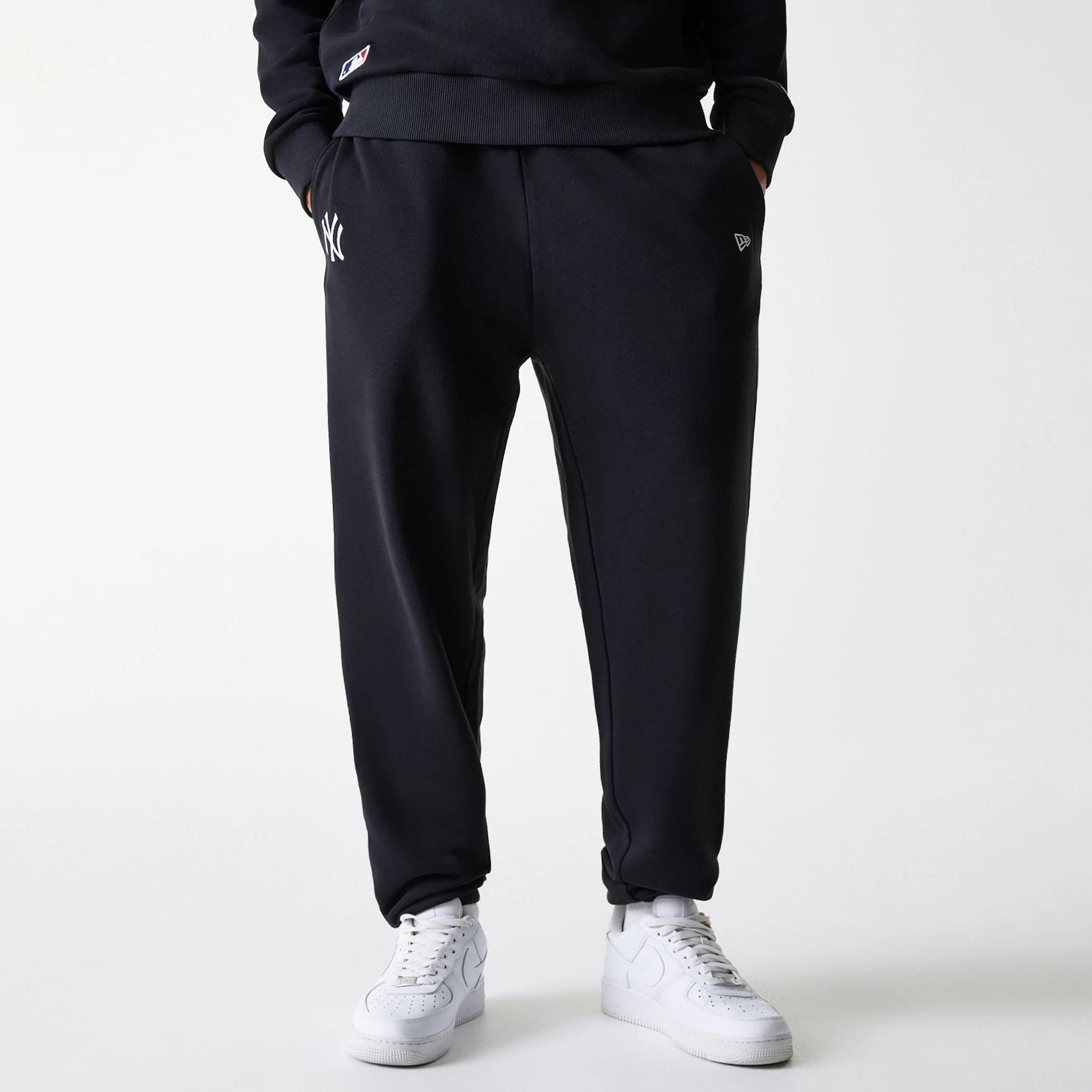 The Male model is wearing New York Yankees MLB League Essential Midi Black Joggers 1