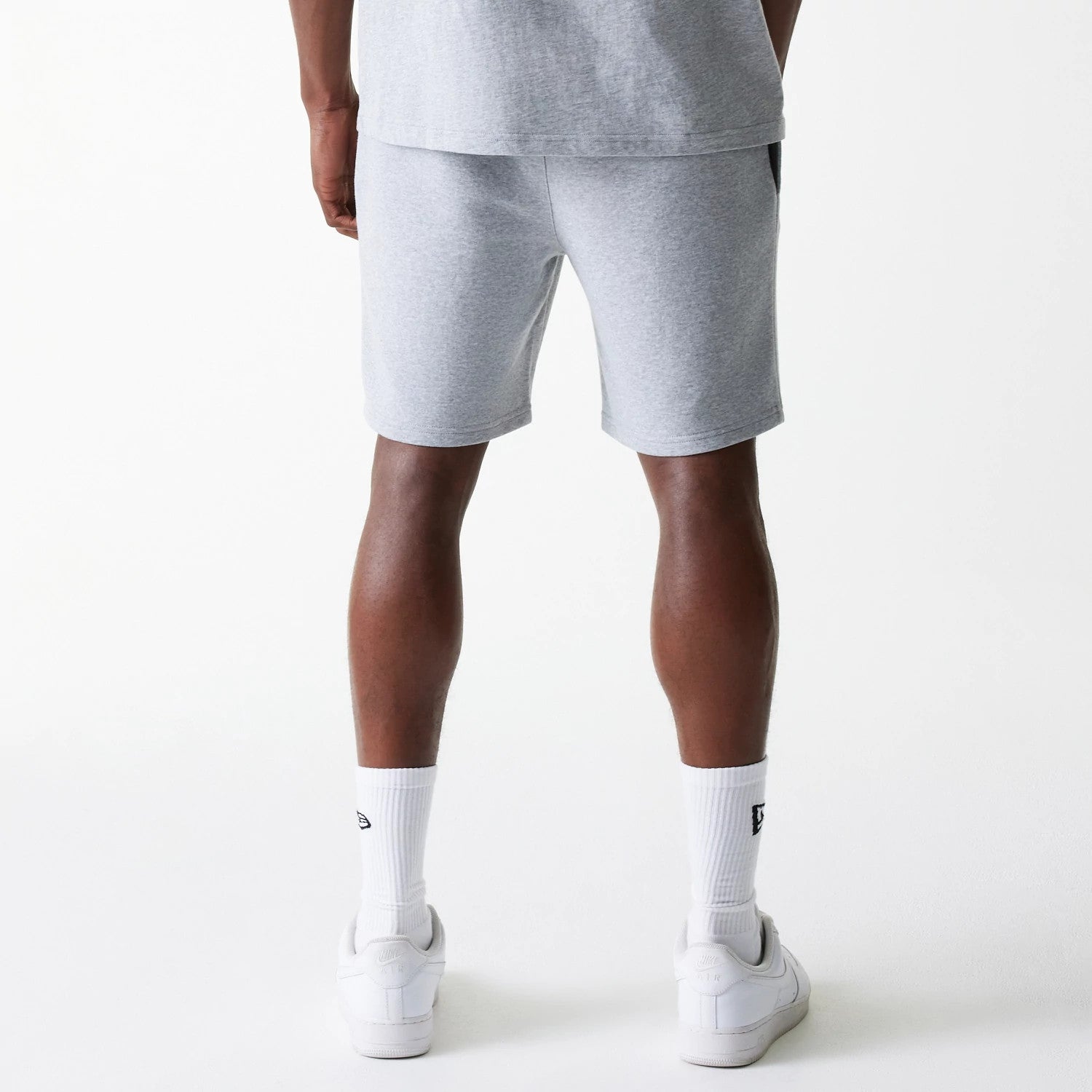 New Era New York Yankees MLB League Essential French Terry Grey Shorts, rear view showing the grey fabric shorts with an elastic waistband, worn by a person with hands by their sides, paired with white socks and sneakers.