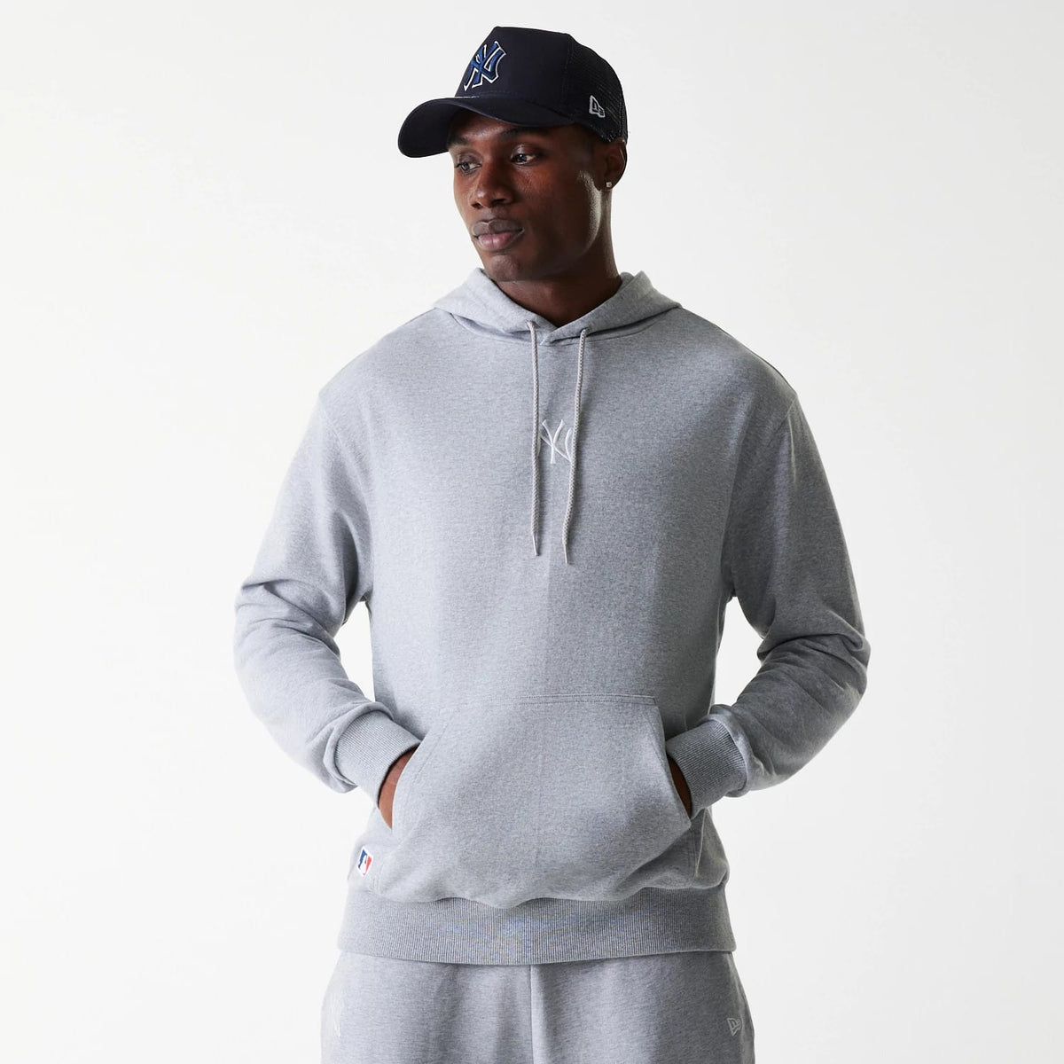 New Era New York Yankees MLB League Essential Midi French Terry Grey Oversized Pullover Hoodie, on-model view showing the grey oversized hoodie with a subtle white New York Yankees logo on the chest and a front kangaroo pocket.