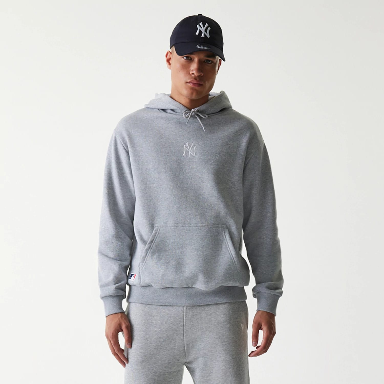 New Era New York Yankees MLB League Essential Grey Oversized Pullover Hoodie, front view showing the relaxed fit grey hoodie with a white raised New York Yankees logo centred on the chest and a drawstring hood.