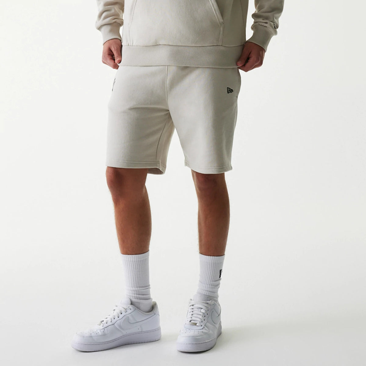 New Era New York Yankees MLB League Essential Midi Cream Shorts, on-model view showing the shorts in cream with a raised New Era logo on the left thigh, featuring an elastic waistband and relaxed fit.