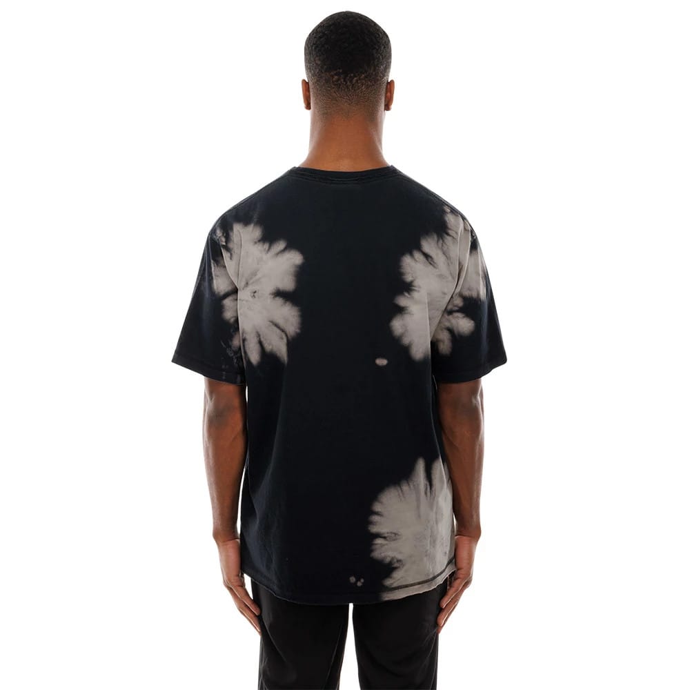 New Era LA Dodgers MLB Bleach Out Black T-Shirt, rear view showing the splattered bleach pattern on the black fabric, short sleeves extending from the shoulders and a straight hemline falling over black trousers.
