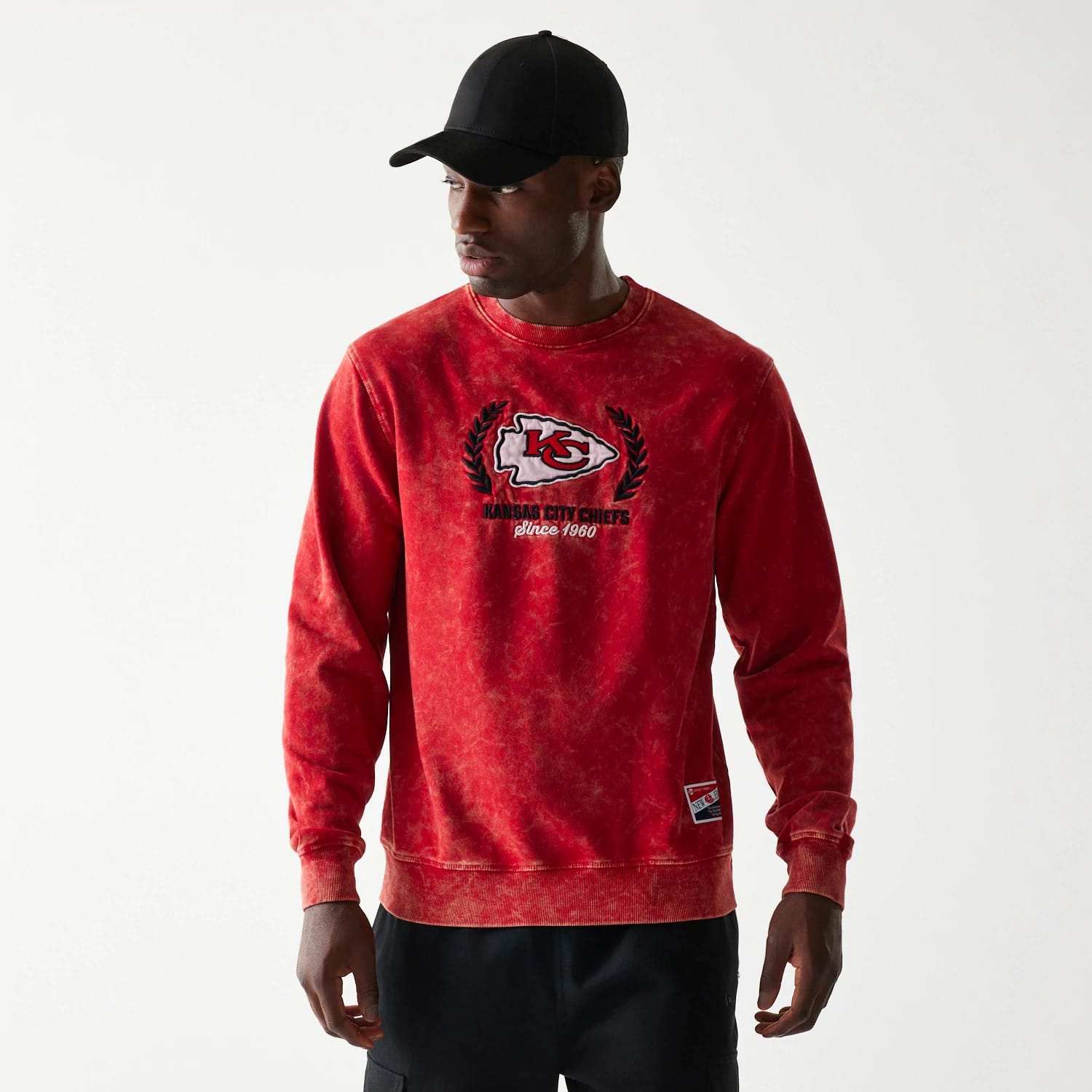New Era Kansas City Chiefs NFL Throwback Red Crew Neck Sweater, front view on a model wearing a black cap, featuring the embroidered Kansas City Chiefs logo and text since 1960 on the chest with a heritage patch near the hem.
