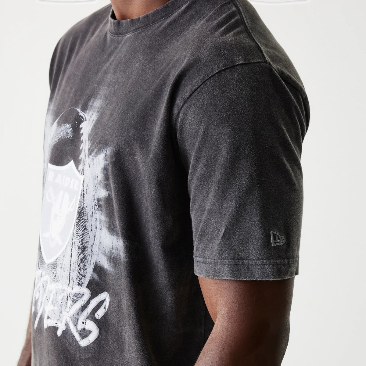 New Era Las Vegas Raiders NFL Sport Night Black T-Shirt, side view showing the grey-black fabric with a large white Raiders logo on the chest, New Era logo debossed on the left sleeve.