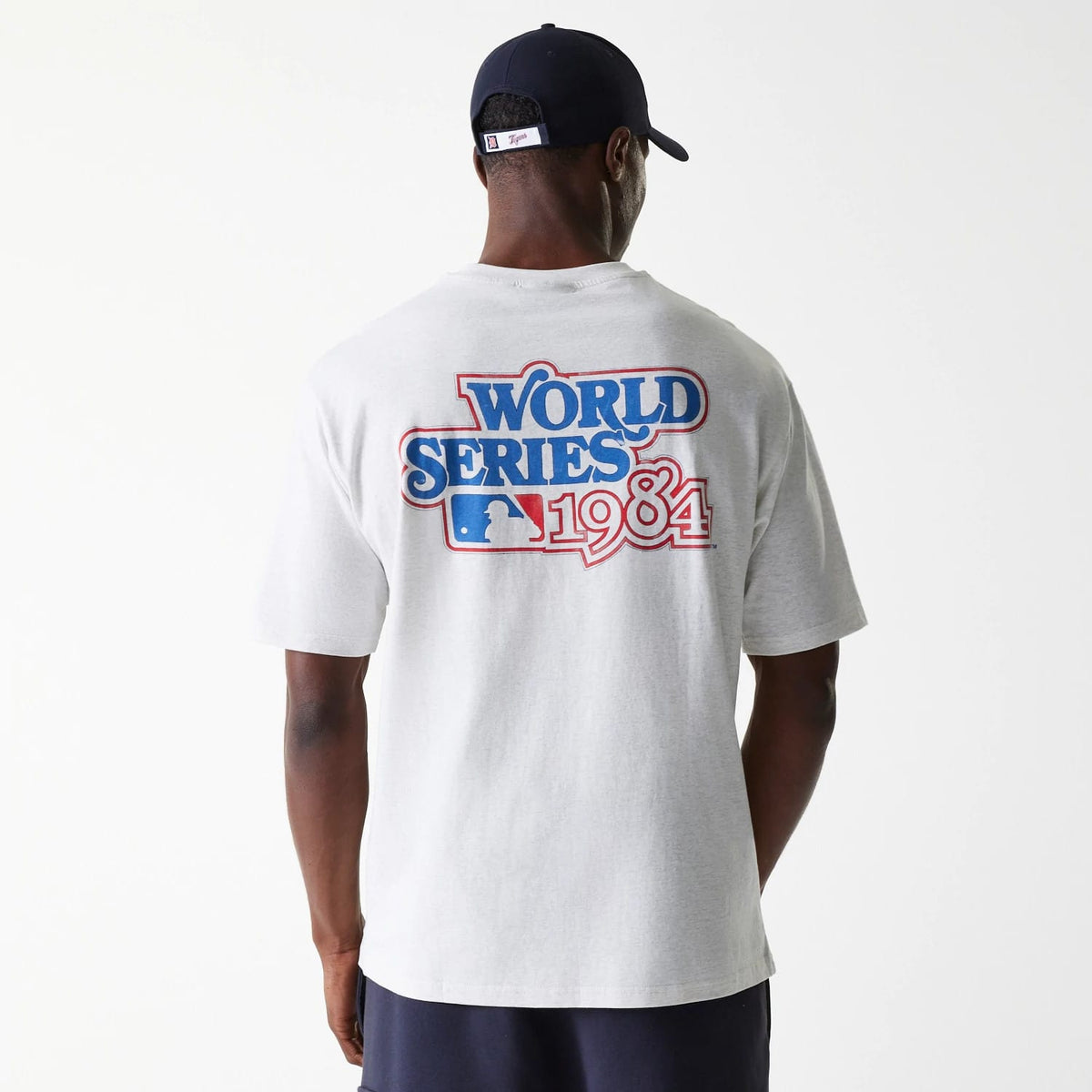 New Era Detroit Tigers MLB World Series Pastel Grey Oversized T-Shirt, back view showing a large blue and red World Series 1984 graphic printed across the upper back, worn by a model with a navy cap.