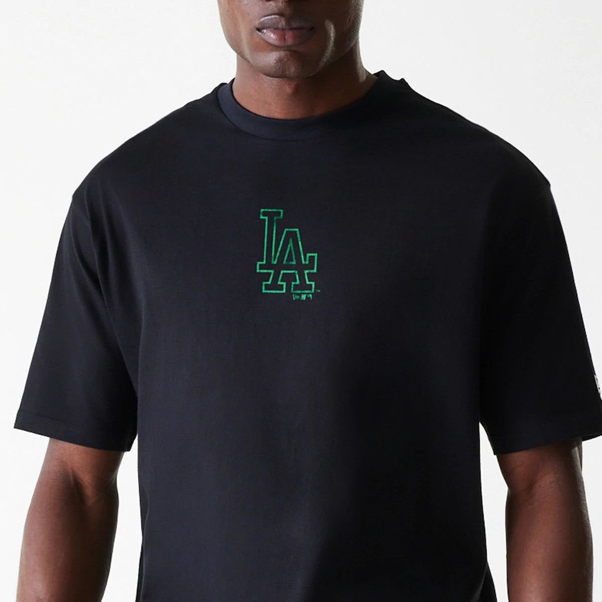New Era LA Dodgers MLB World Series Black Oversized T-Shirt, front view showing a black T-shirt with a green embroidered LA Dodgers logo centred on the chest, short sleeves, and a round neckline.