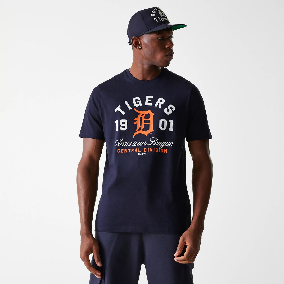 New Era Detroit Tigers MLB Wordmark Navy T-Shirt, on-model view showing the navy shirt with large white and orange Detroit Tigers graphics across the chest, paired with a navy cap featuring raised Detroit Tigers text.
