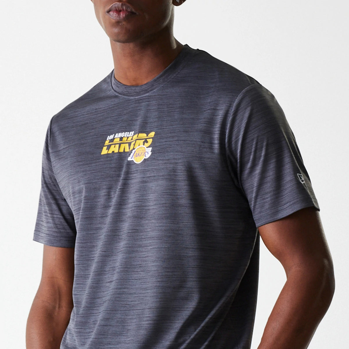 New Era LA Lakers NBA Essentials Black T-Shirt, on-model view showing the grey textured fabric with a raised yellow and white LA Lakers logo centred on the chest and a small raised New Era logo on the left sleeve.